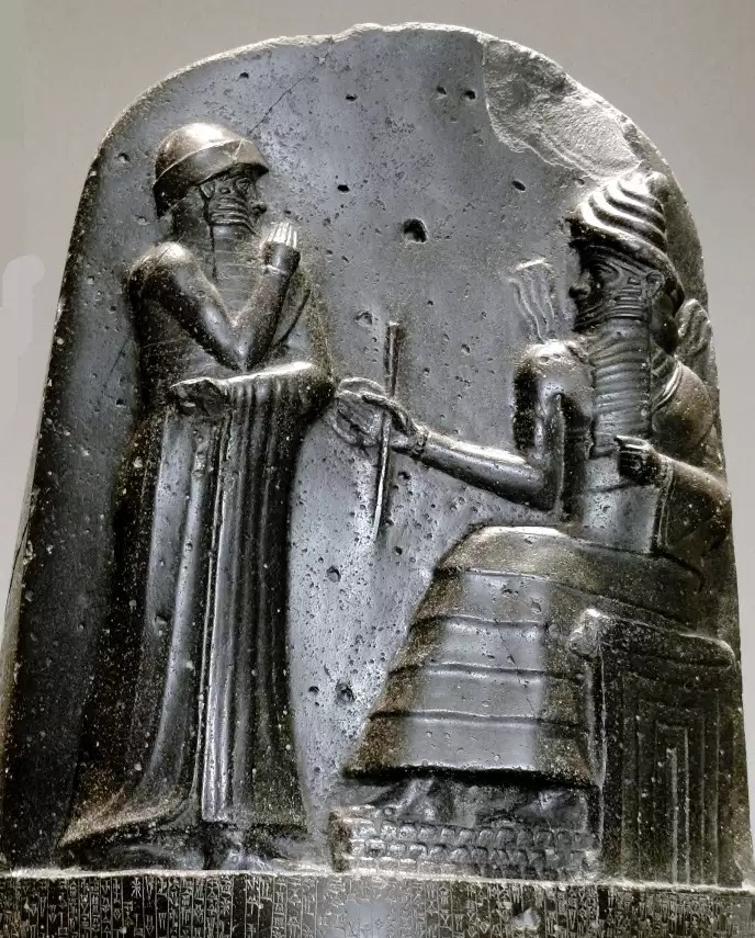 XVIIIe siècle avant notre ère, musée du Louvre. Dans le Proche-Orient ancien, ce sont traditionnellement les dieux (ici, Mardouk) qui remettent aux rois (ici, Hammourabi de Babylone) les insignes liées à leur fonction.